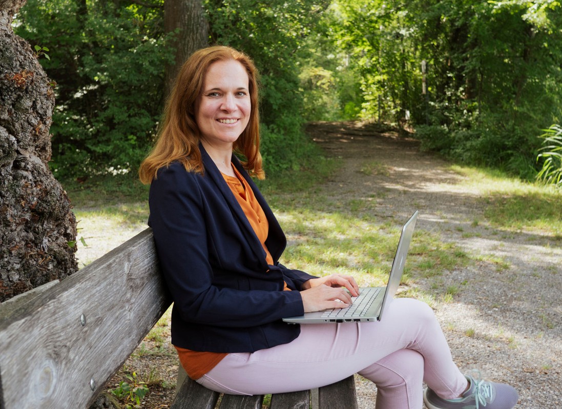 Alexandra Vukits mit Laptop auf einer Bank